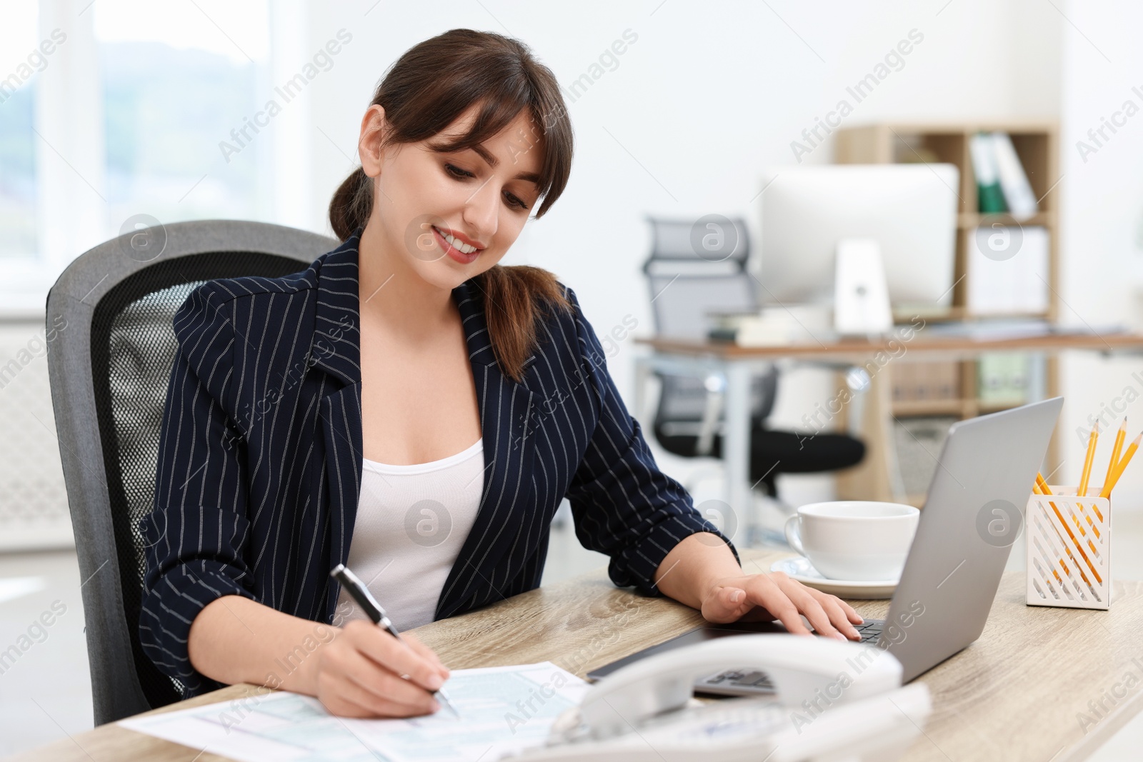 Photo of Smiling secretary working at table in office