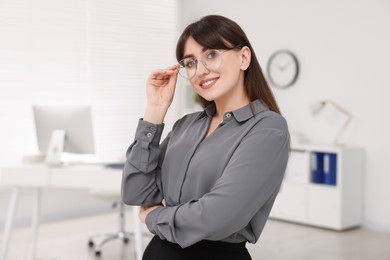 Photo of Portrait of smiling secretary wearing glasses in office
