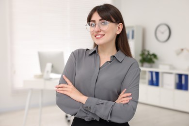 Photo of Portrait of smiling secretary with crossed arms in office