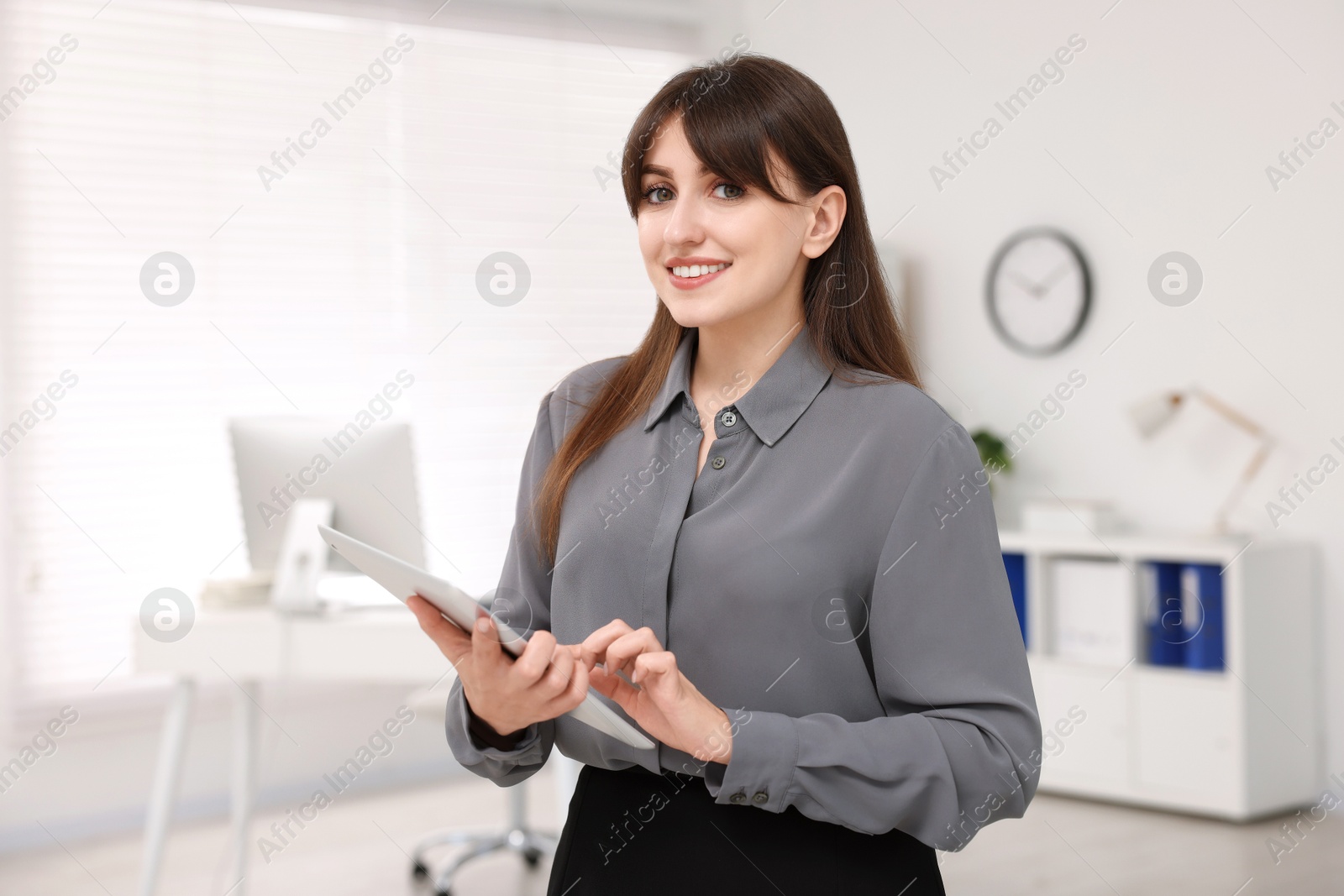 Photo of Portrait of smiling secretary with tablet in office
