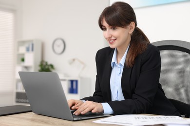 Photo of Smiling secretary working at table in office