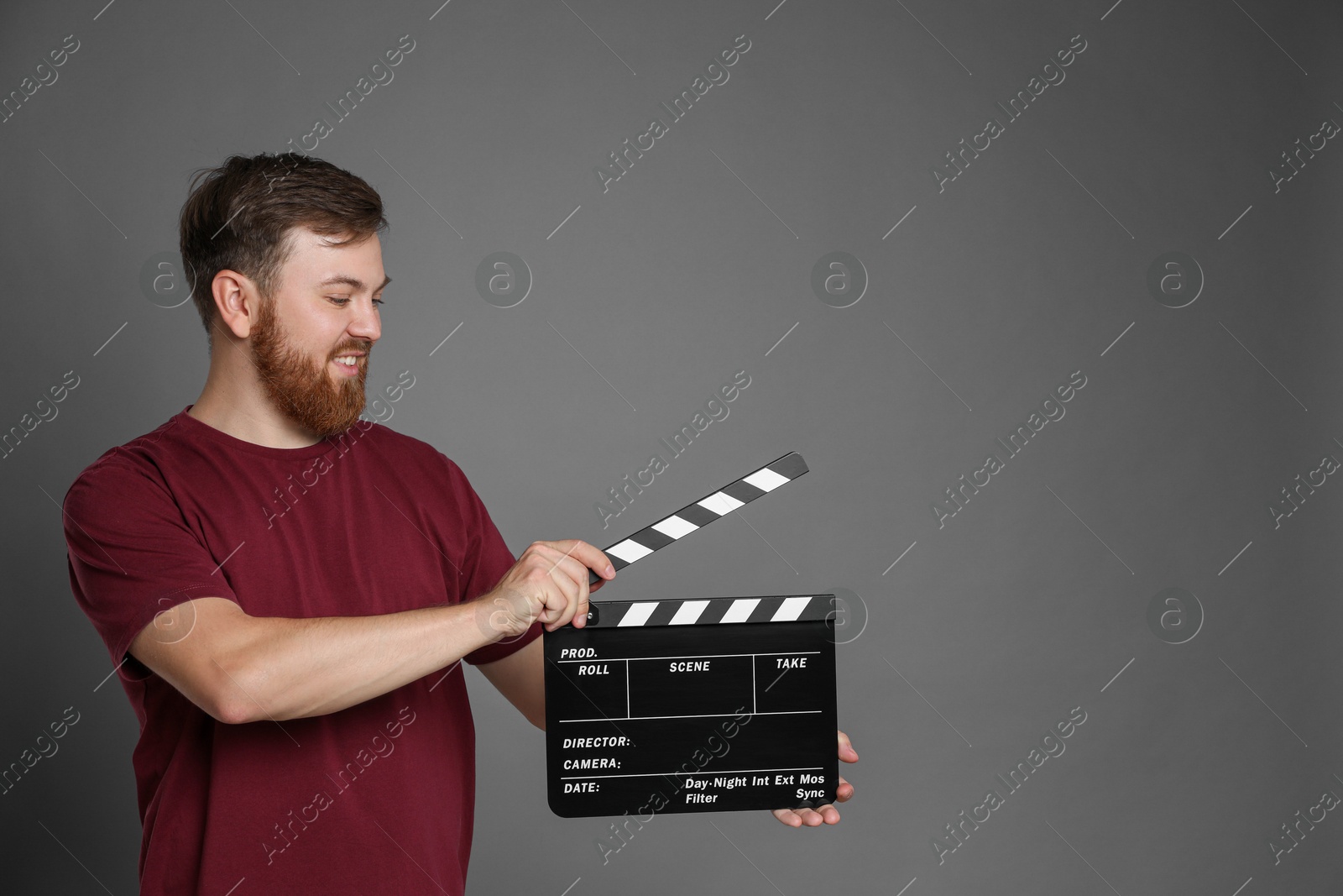 Photo of Making movie. Smiling man with clapperboard on grey background. Space for text