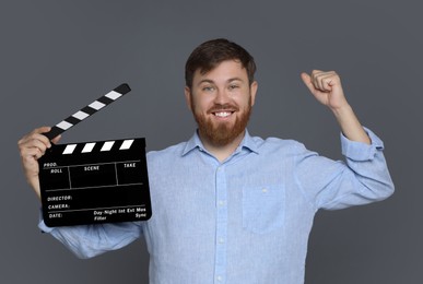 Photo of Making movie. Happy man with clapperboard on grey background