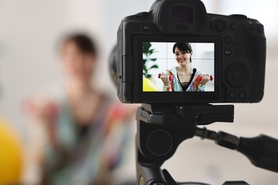 Happy sports blogger with dumbbells recording fitness lesson at home, focus on camera