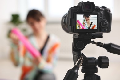 Happy sports blogger with resistance band recording fitness lesson at home, focus on camera