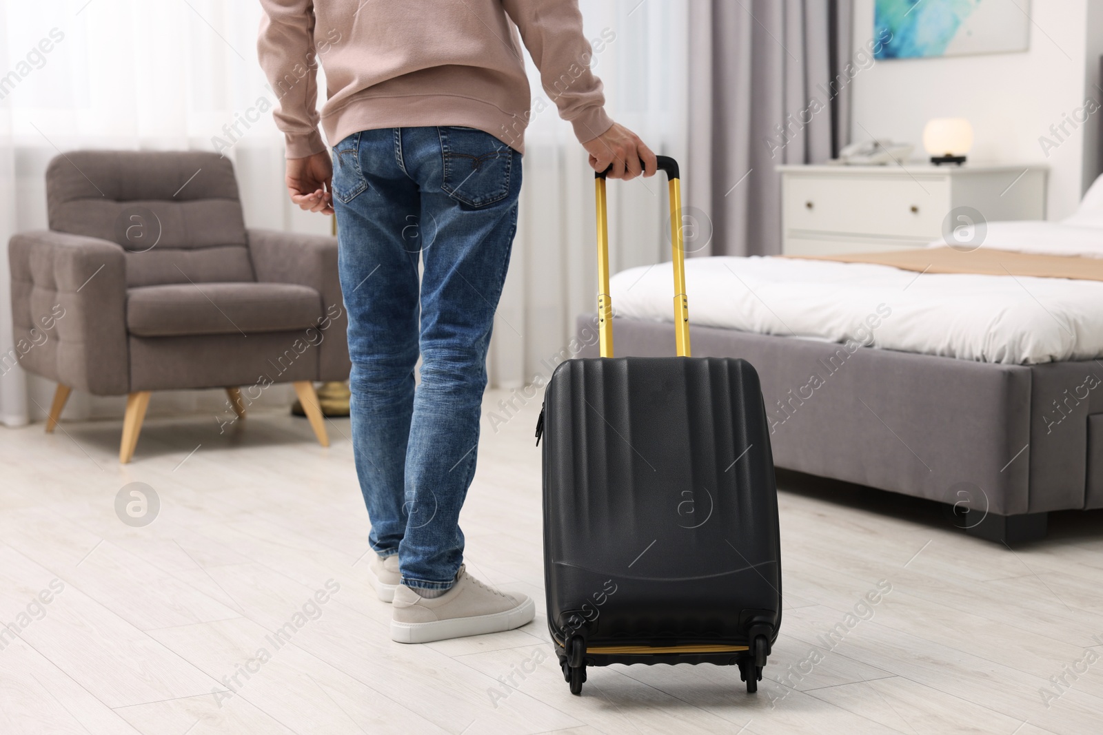 Photo of Guest with suitcase walking in hotel room, closeup