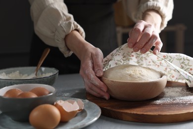 Photo of Woman covering dough with napkin at grey table, closeup