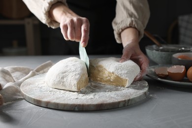 Photo of Woman cutting dough at grey table, closeup