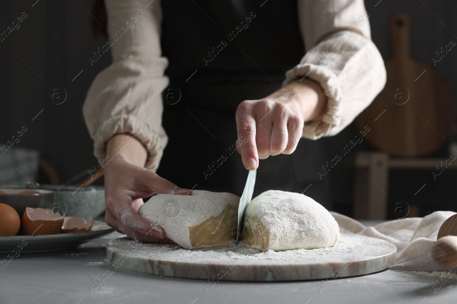 Photo of Woman cutting dough at grey table, closeup