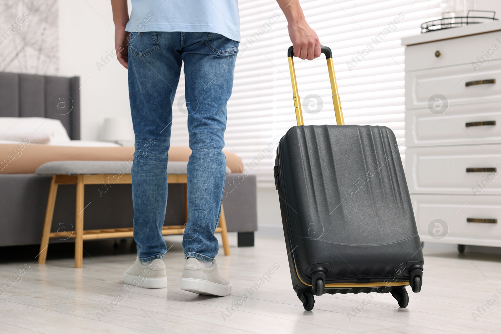 Photo of Guest with suitcase walking in hotel room, closeup