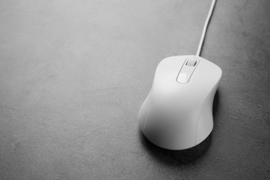 One wired mouse on black textured table, closeup. Space for text