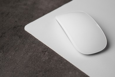 Photo of One wireless mouse with mousepad on black textured table, closeup. Space for text