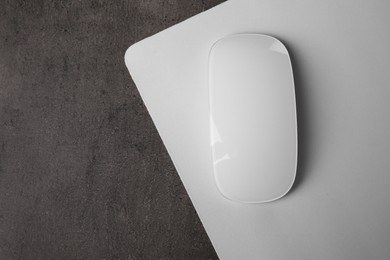 One wireless mouse with mousepad on black textured table, top view. Space for text