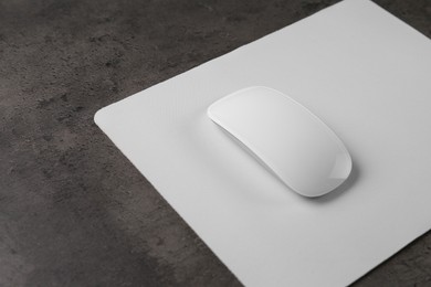 Photo of One wireless mouse with mousepad on black textured table, closeup. Space for text