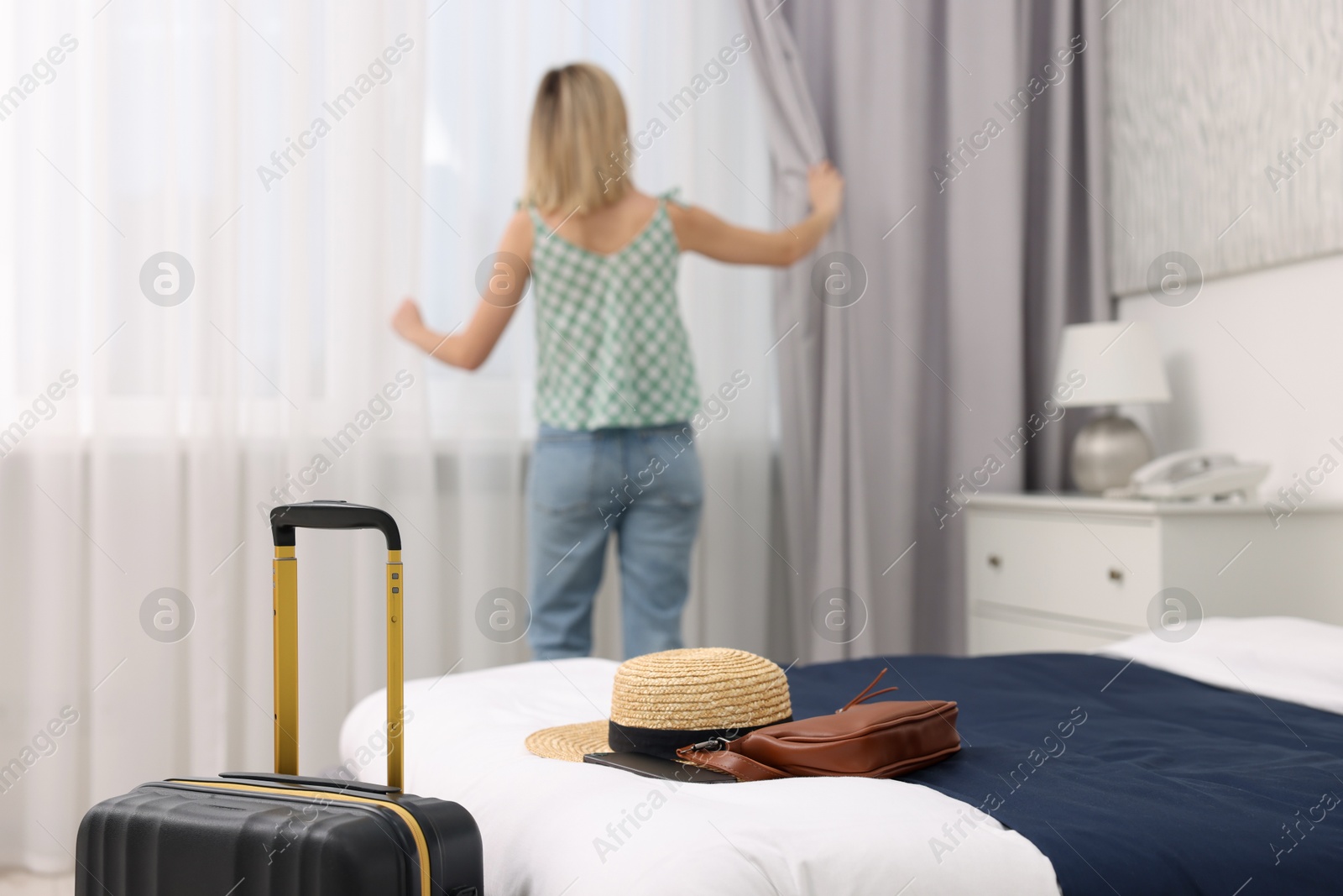 Photo of Guest opening curtains in stylish hotel room, selective focus