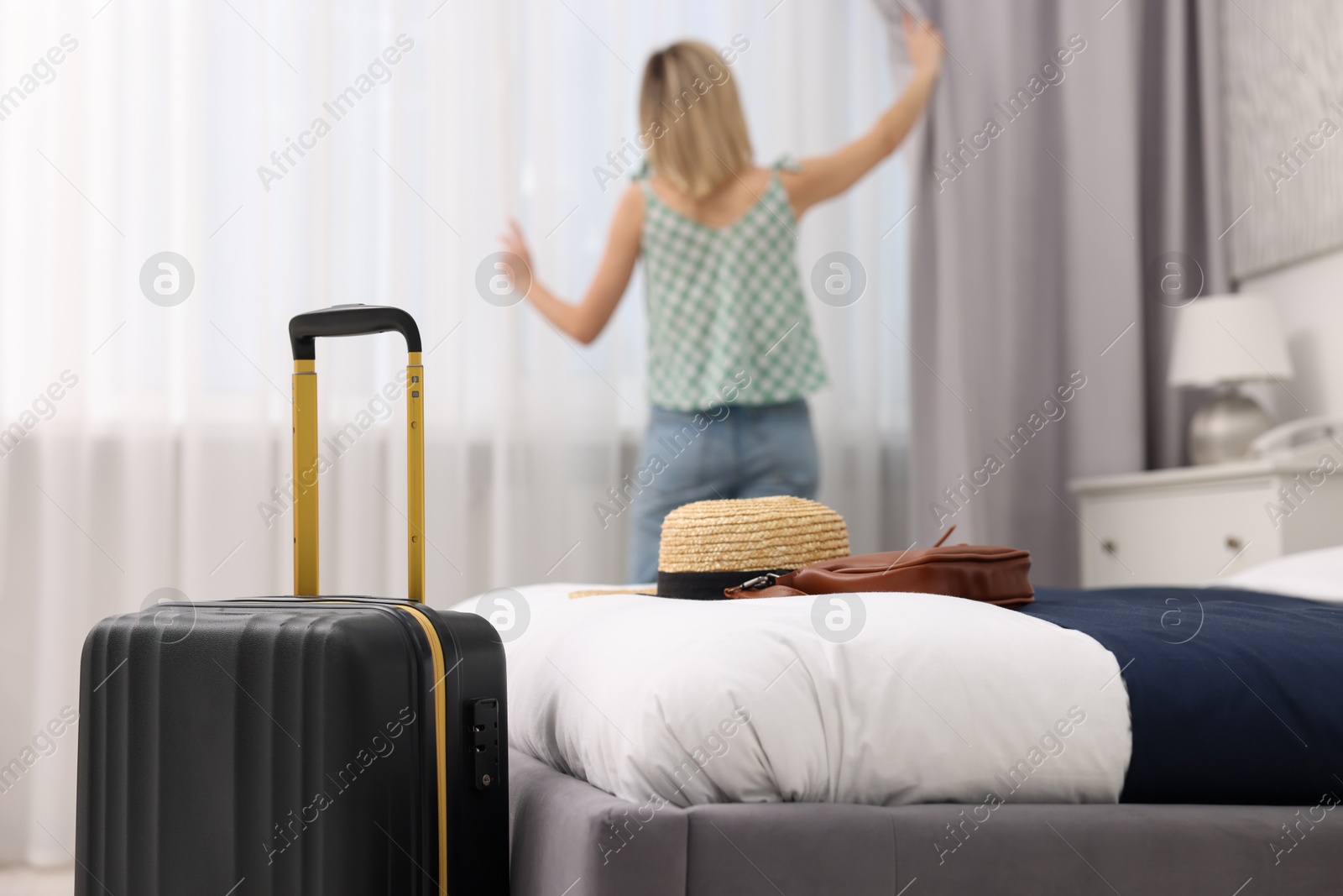 Photo of Guest opening curtains in stylish hotel room, selective focus