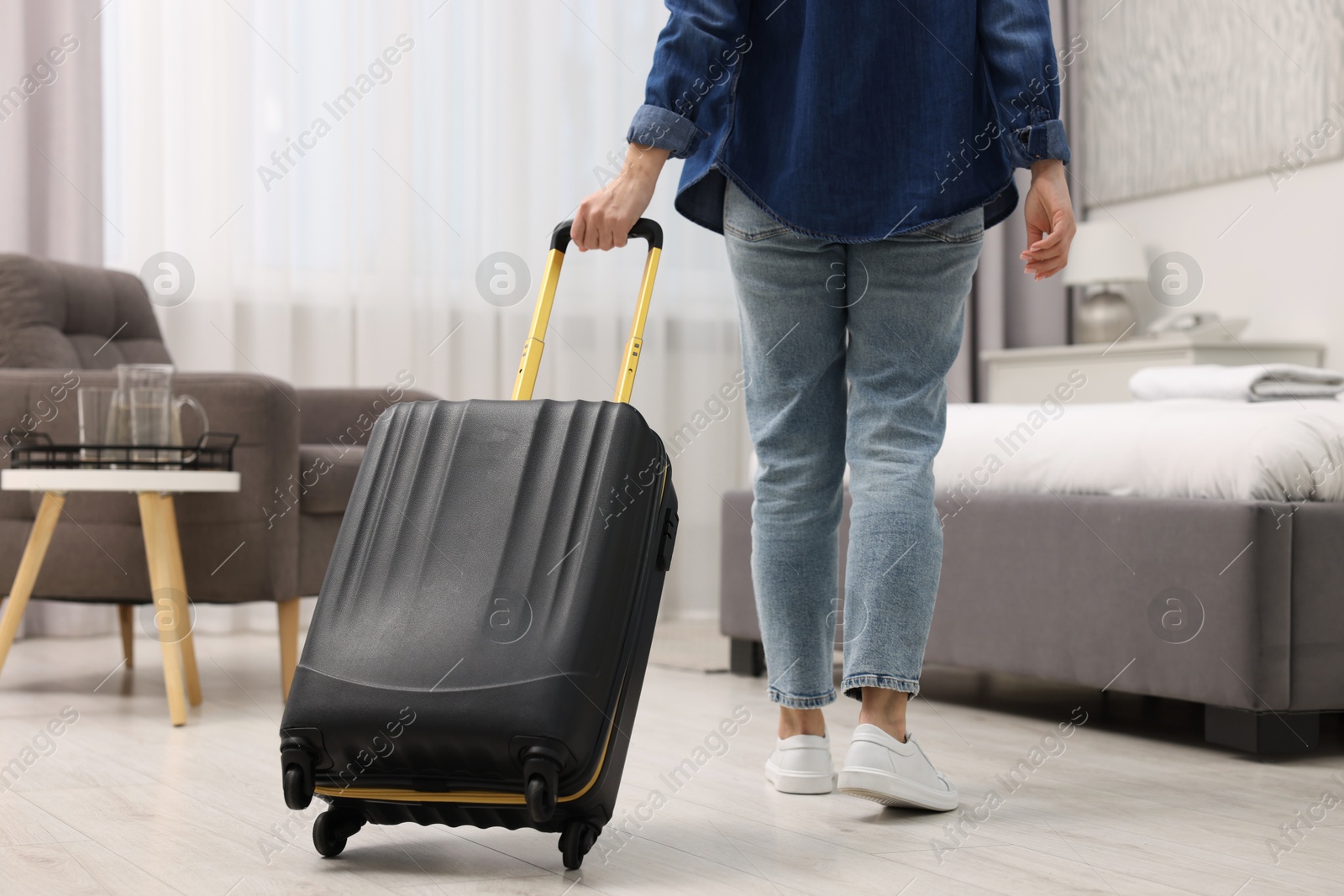 Photo of Guest with suitcase walking in hotel room, closeup