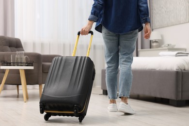 Guest with suitcase walking in hotel room, closeup