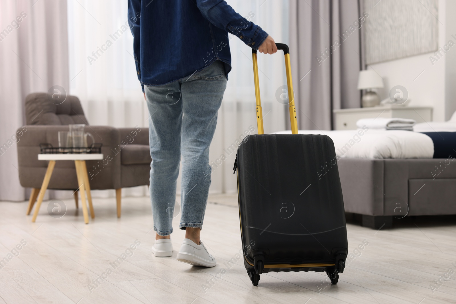 Photo of Guest with suitcase walking in hotel room, closeup