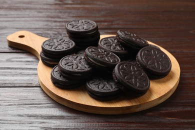 Photo of Board with tasty sandwich cookies on wooden table, closeup