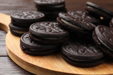 Photo of Board with tasty sandwich cookies on wooden table, closeup