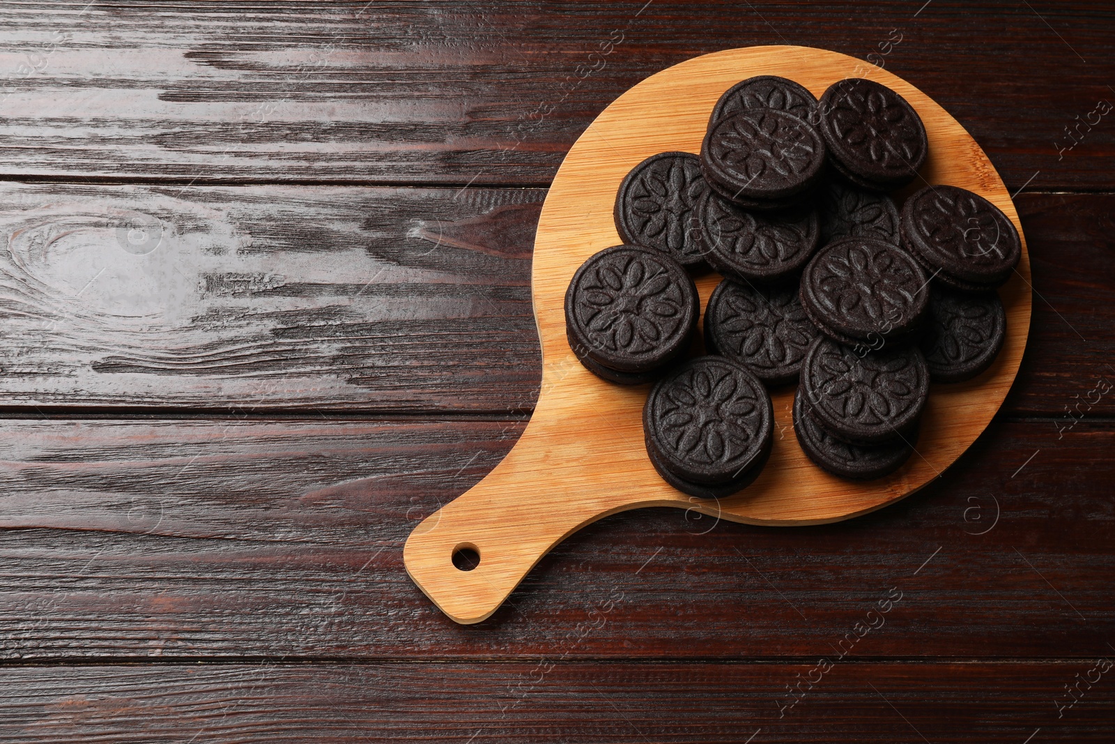 Photo of Board with tasty sandwich cookies on wooden table, top view. Space for text