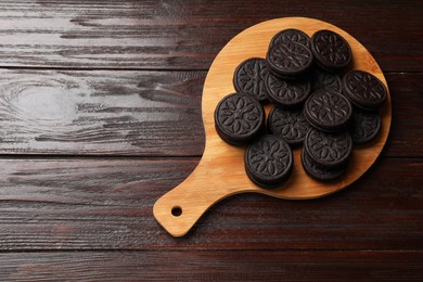 Photo of Board with tasty sandwich cookies on wooden table, top view. Space for text