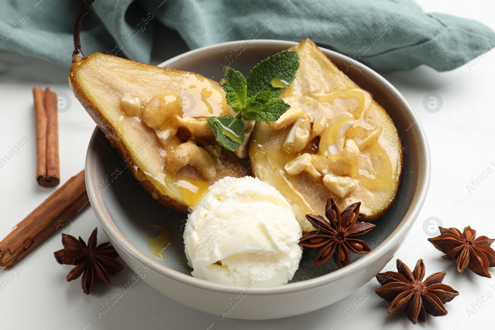 Photo of Delicious baked pears with nuts, ice cream, anise stars, mint and honey in bowl on white table, closeup