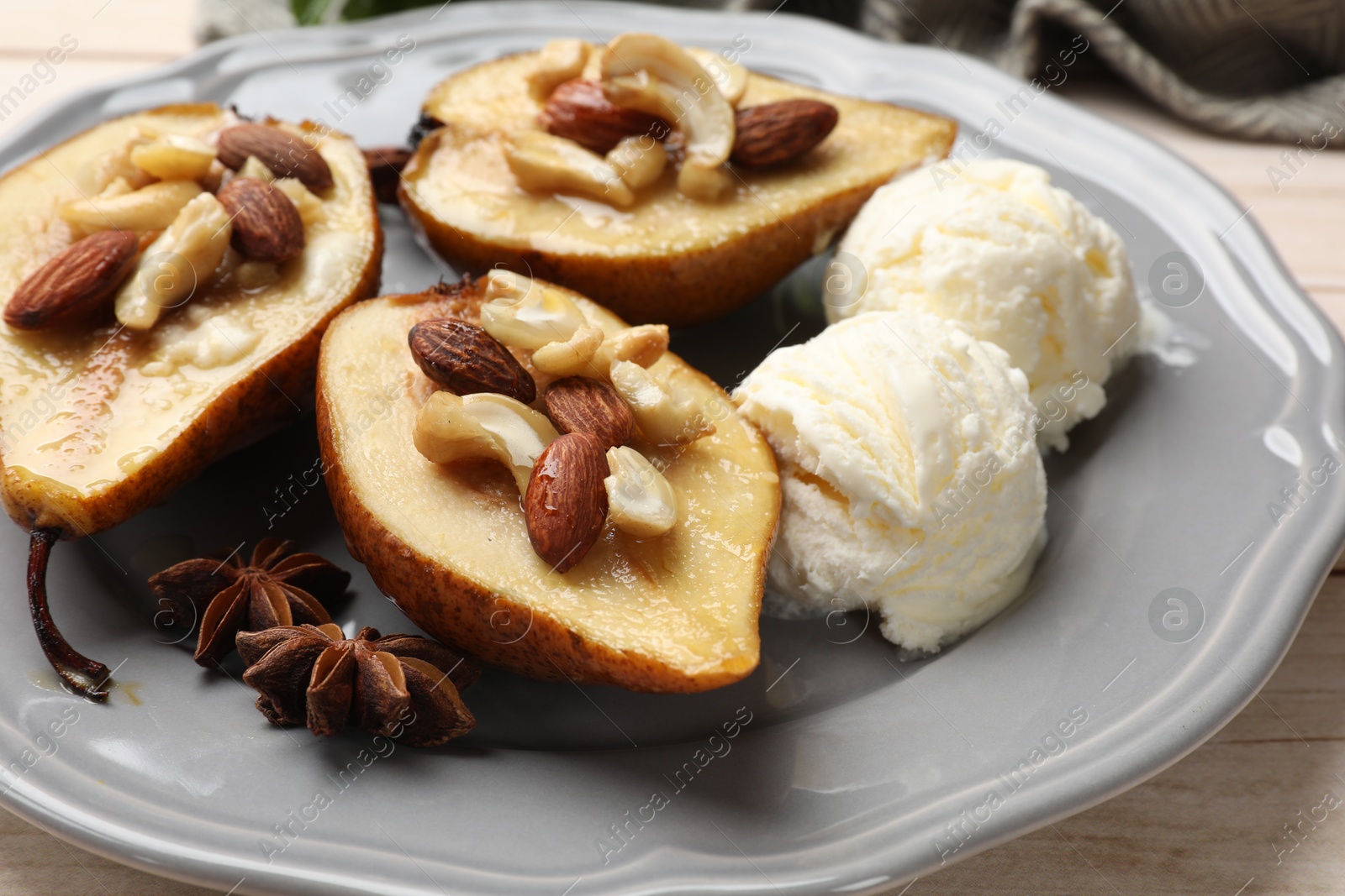 Photo of Delicious baked pears with nuts, ice cream, anise stars and honey on light wooden table, closeup