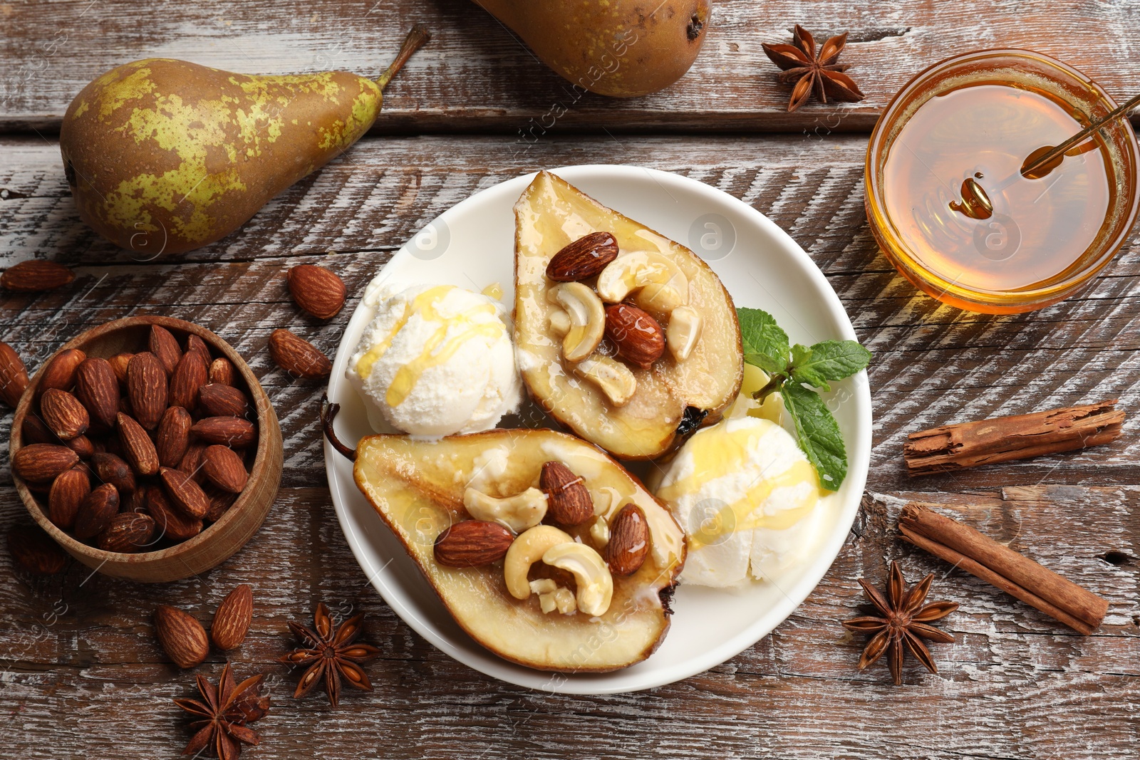 Photo of Delicious baked pears with nuts, ice cream, anise stars and honey on wooden rustic table, flat lay