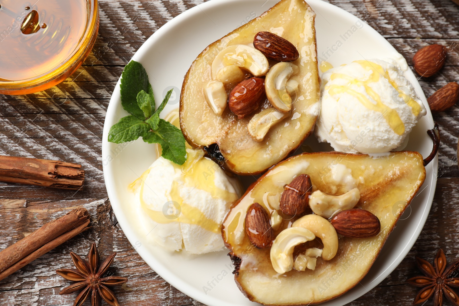 Photo of Delicious baked pears with nuts, ice cream, anise stars and honey on wooden rustic table, flat lay