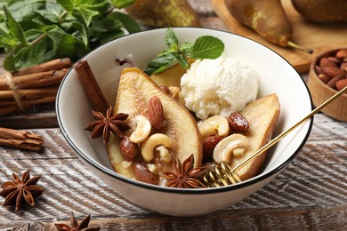 Delicious baked pears with nuts, ice cream, anise stars, dipper and honey in bowl on wooden rustic table, closeup