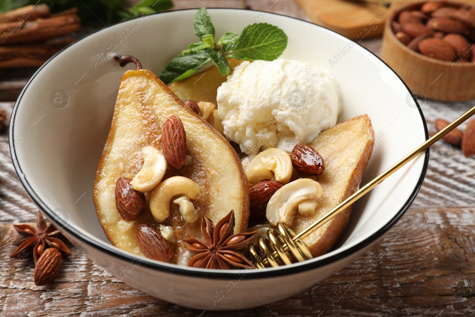 Photo of Delicious baked pears with nuts, ice cream, anise stars, dipper and honey in bowl on wooden rustic table, closeup