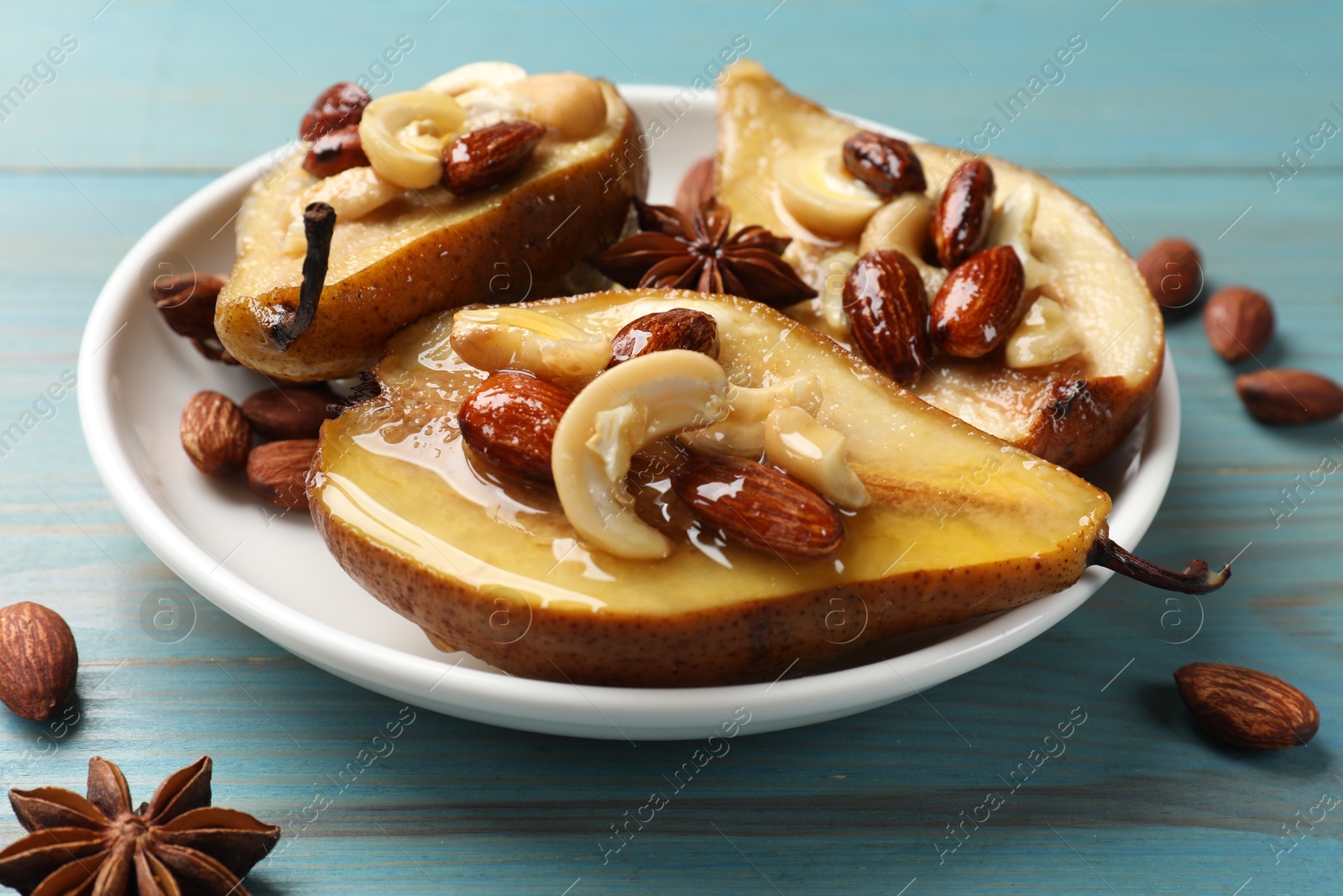 Photo of Delicious baked pears with nuts, anise stars and honey on light blue wooden table, closeup