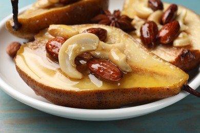 Photo of Delicious baked pears with nuts and honey on light blue wooden table, closeup