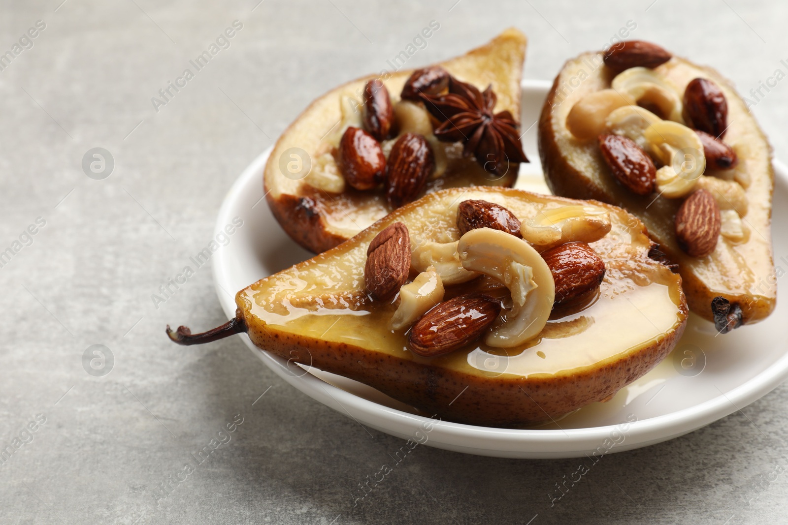 Photo of Delicious baked pears with nuts and honey on grey textured table, closeup
