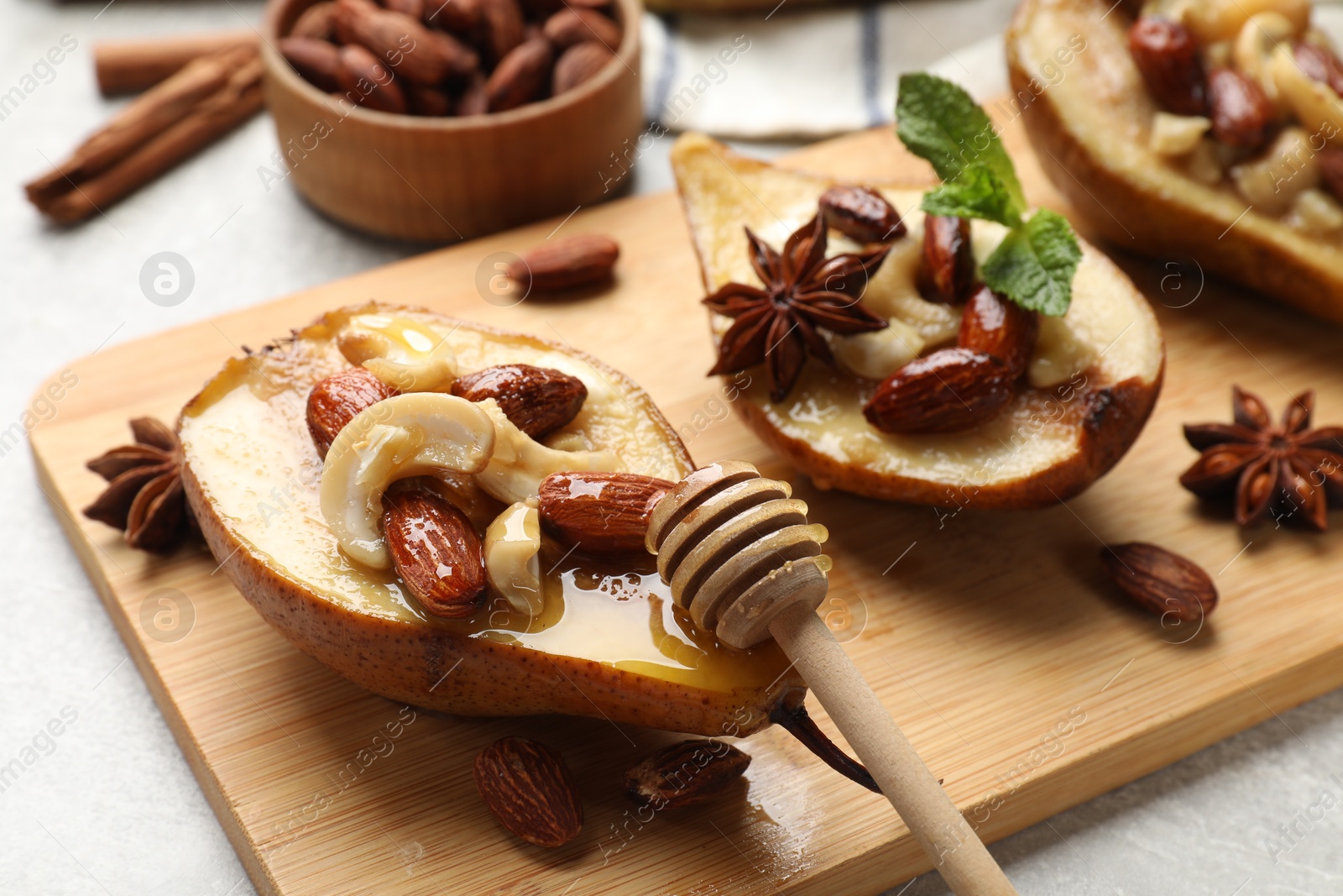 Photo of Delicious baked pears with nuts, honey, dipper and anise stars on light textured table, closeup