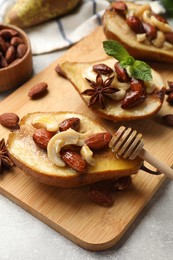 Photo of Delicious baked pears with nuts, honey, dipper and anise stars on light textured table, closeup