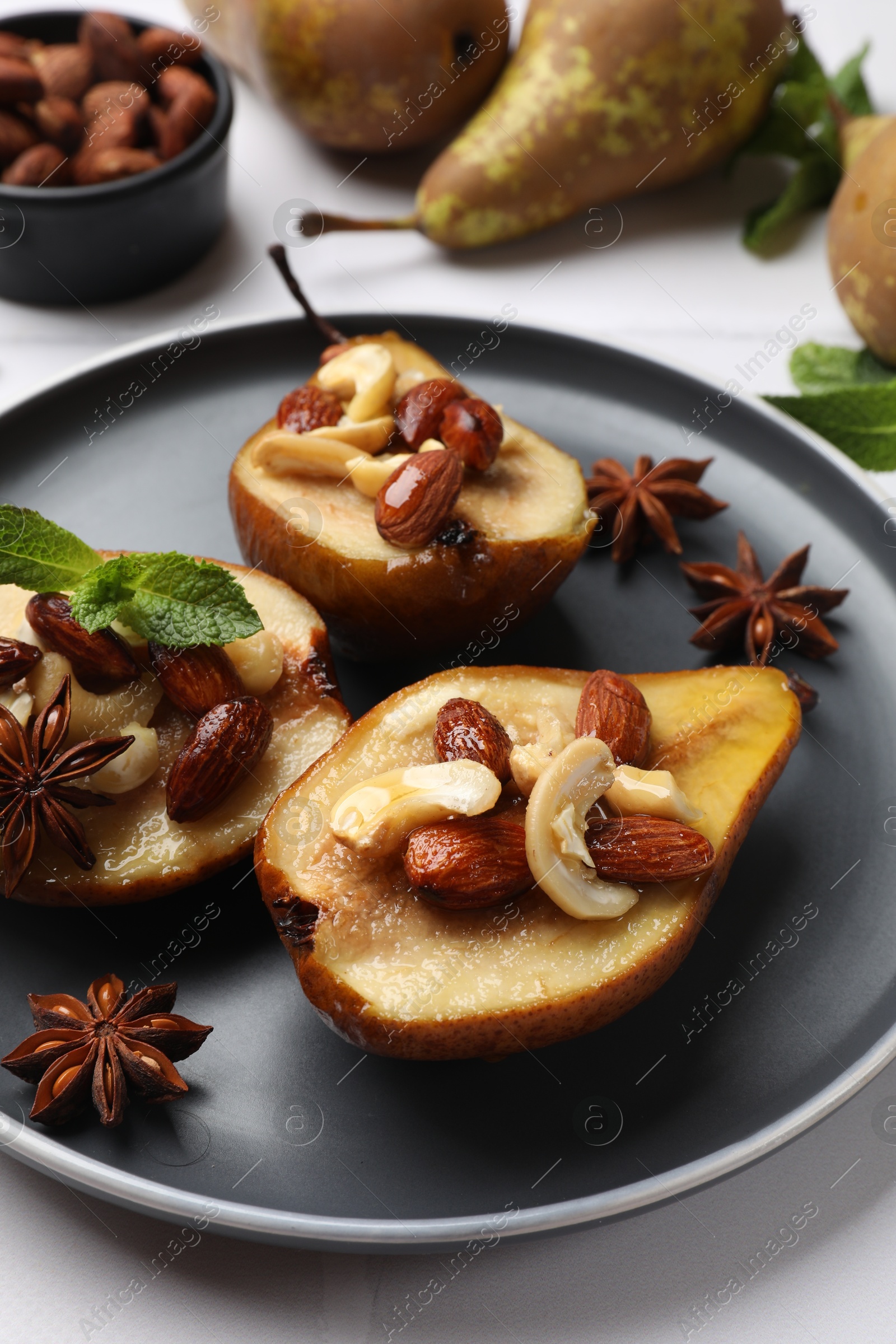 Photo of Delicious baked pears with nuts and anise stars on white table, closeup