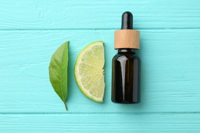 Photo of Bottle of essential oil, lime and green leaf on turquoise wooden table, flat lay