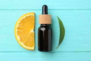 Bottle of essential oil, orange and green leaf on turquoise wooden table, flat lay