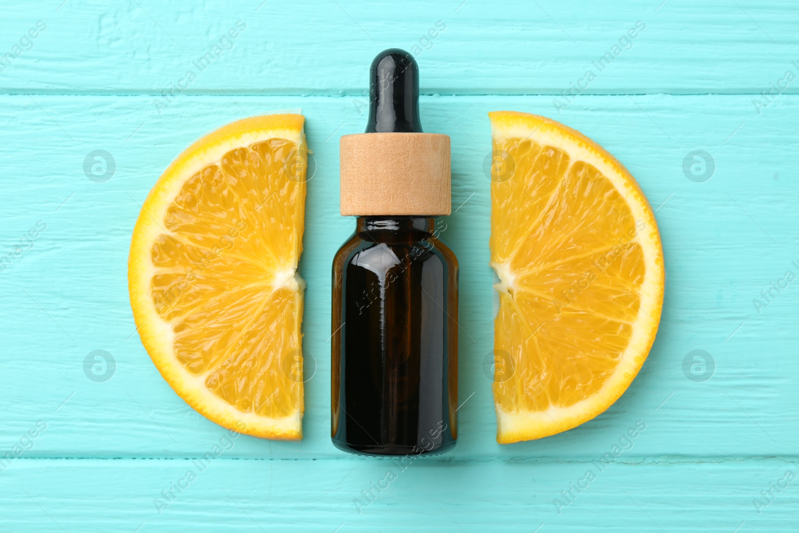 Photo of Bottle of essential oil and orange on turquoise wooden table, flat lay