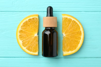 Photo of Bottle of essential oil and orange on turquoise wooden table, flat lay