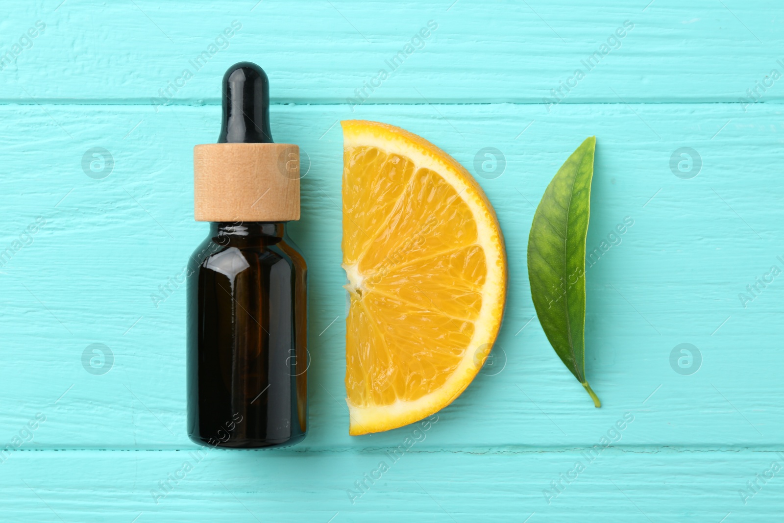 Photo of Bottle of essential oil, orange and green leaf on turquoise wooden table, flat lay