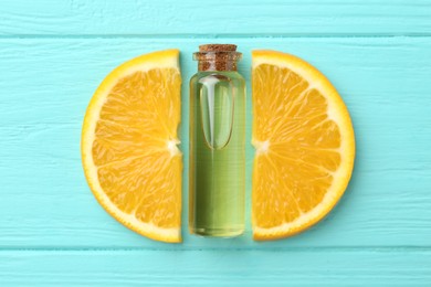 Photo of Bottle of essential oil and orange on turquoise wooden table, top view