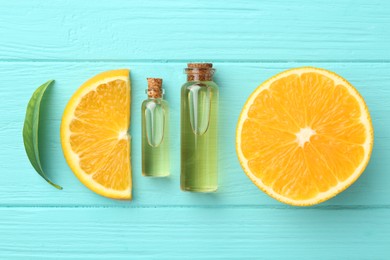 Photo of Bottles of essential oils, orange and green leaf on turquoise wooden table, flat lay