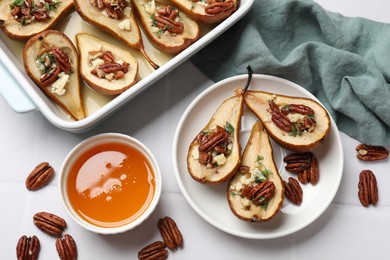 Delicious baked pears with nuts, blue cheese, thyme and honey on white tiled table, flat lay