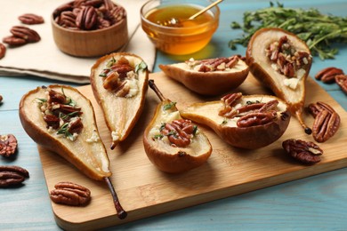 Photo of Delicious baked pears with nuts, blue cheese, thyme and honey on light blue wooden table, closeup