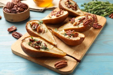 Photo of Delicious baked pears with nuts, blue cheese, thyme and honey on light blue wooden table, closeup