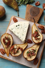 Photo of Delicious baked pears with nuts, blue cheese, thyme and honey on light blue wooden table, flat lay